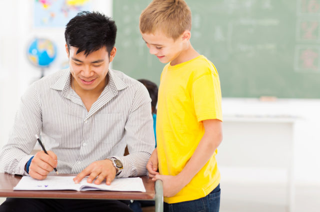 shutterstock cheerful young male teacher grading school boy's work marking