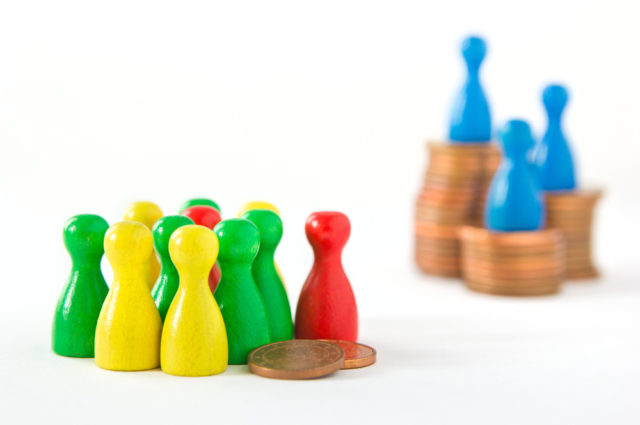 shutterstock_303577874 group of game figurines huddling around two cents while very few are on top of stacks, concept: unequal distribution of wealth