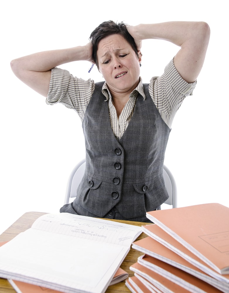 shutterstock_164481656 stressed teacher trying to mark a pile of students work