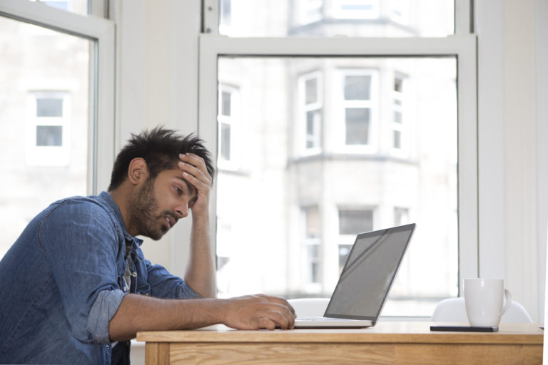 shutterstock_213985702 Stressed and frustrated Asian man sitting at his laptop.