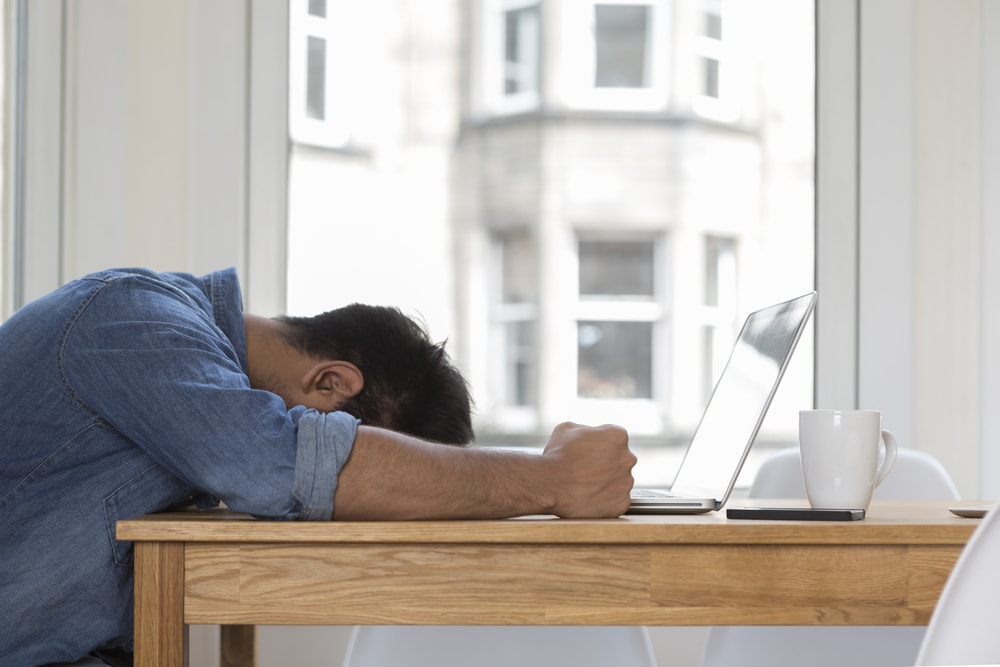 shutterstock_213985705 Stressed and frustrated Asian man sitting at his laptop.
