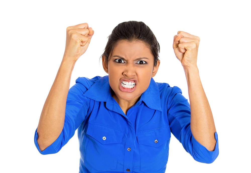 shutterstock_173097173 Closeup portrait of bitter displeased pissed, angry cranky grumpy woman teeth growling, fists in air about to bash something, isolated on white background. Negative emotion facial expression feeling