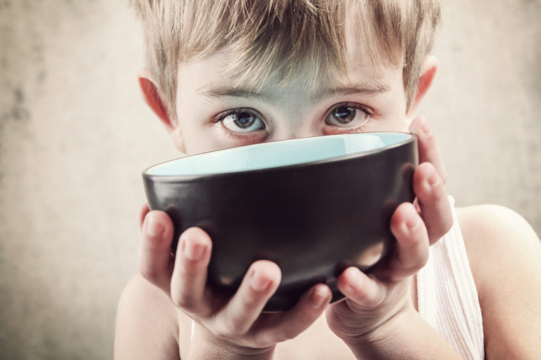 shutterstock_219628963 Toned image of a hungry child holding an empty bowl.