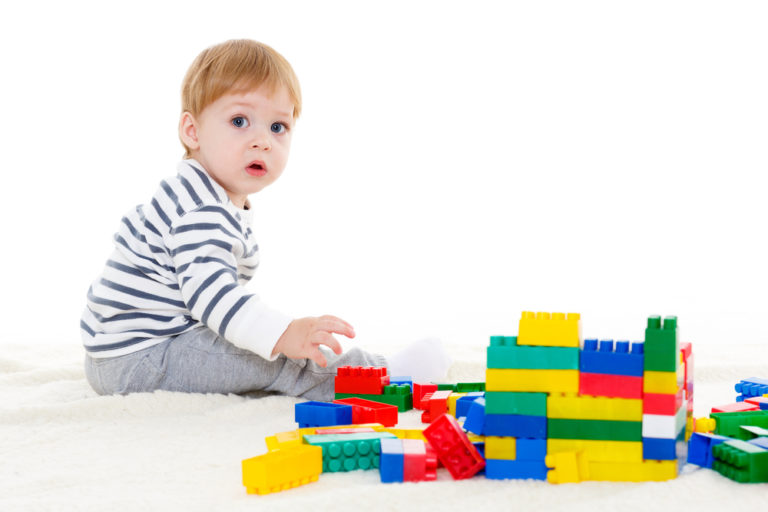 shutterstock_246059848 Little sweet boy plays with children blocks set on a white background. Early development and learning toys.