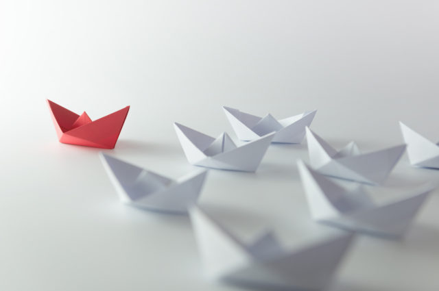 shutterstock_224882329 Leadership concept using red paper ship among white