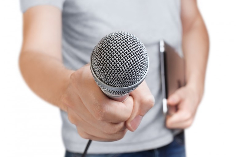 shutterstock_261065645 Young man holding a microphone, isolated on white background