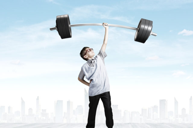 shutterstock_200446283 Cute boy of school age lifting barbell above head