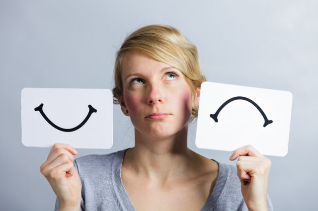 shutterstock_267055247 Portrait of a Questioning Woman Holding Happy and Unhappy Survey Mood Board
