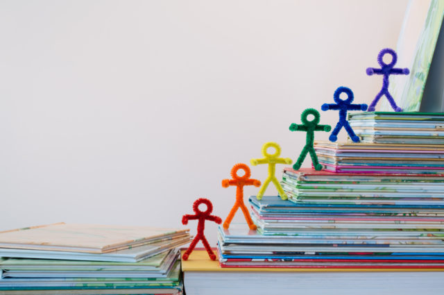 shutterstock_294167084 A happy line of rainbow pipe-cleaner people going up the ladder of success through reading and education. A lovely photo for international or multicultural ideas and concepts for adults and children.