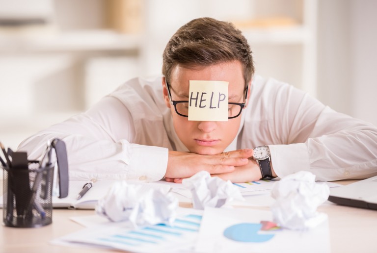shutterstock_308806613 Frustrated young businessman in his office with adhesive note on his forehead. He needs help.