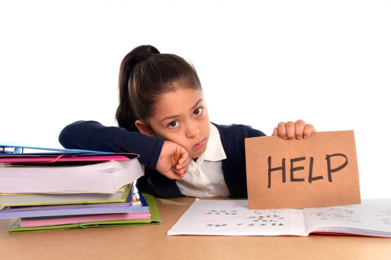 shutterstock_215271067 sweet little female latin child studying on desk asking for help in stress with a tired face expression in children education and back to school concept isolated on white background