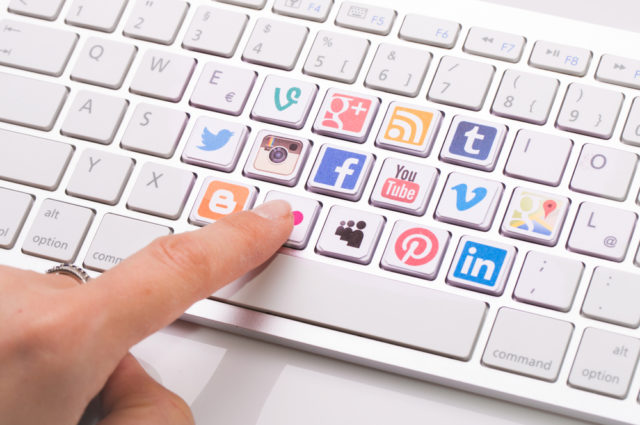 shutterstock_218622676 BELCHATOW, POLAND - AUGUST 31, 2014: Male hand pointing on key with a social media logotype collection printed and placed on modern computer keyboard.