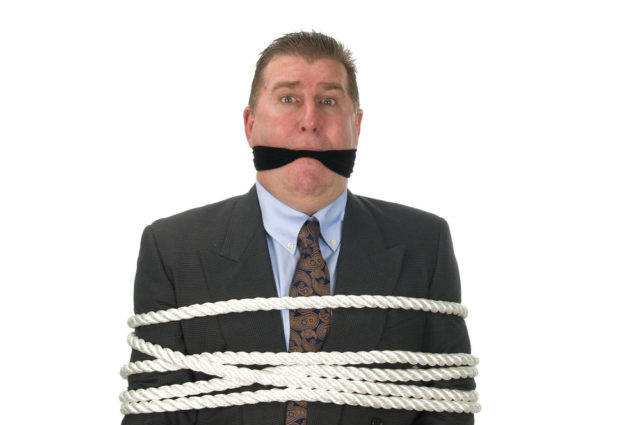shutterstock_22852555 A businessman is tied up by angry co-workers.