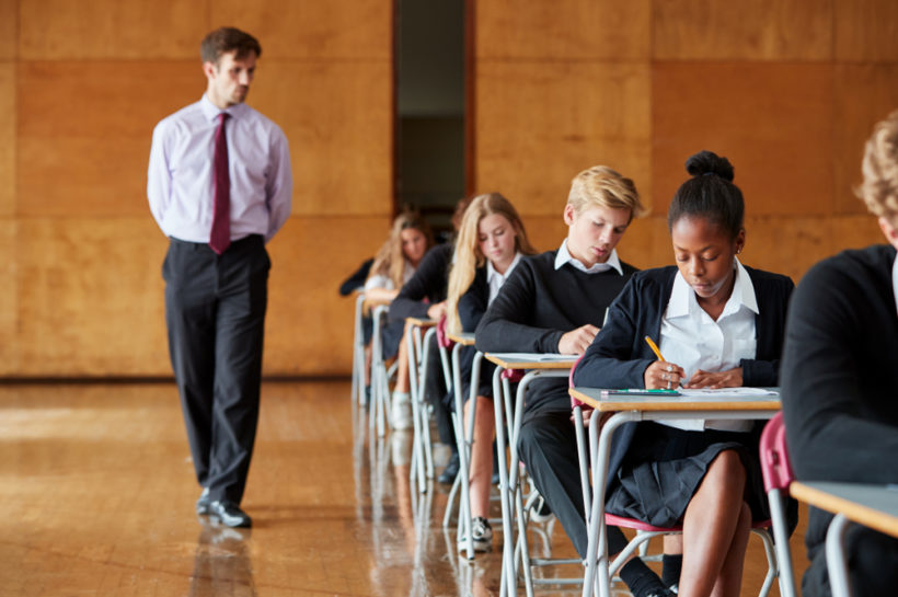 Teenage Students Sitting Examination With Teacher Invigilating - Image