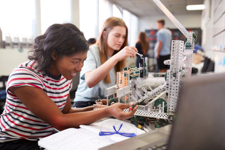 Two,female,college,students,building,machine,in,science,robotics,or