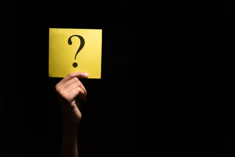 Hand,holding,a,yellow,paper,with,question,mark,in,a