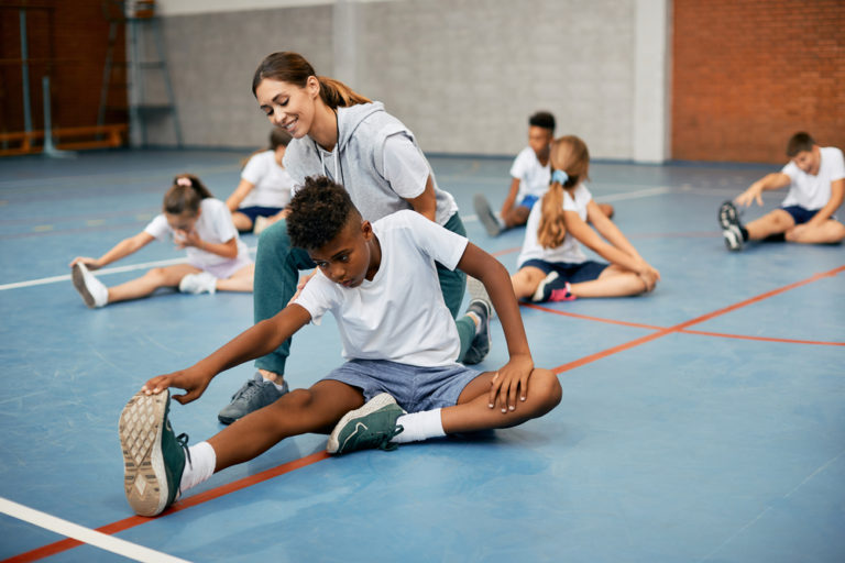 Black,school,boy,stretching,on,the,floor,with,help,of