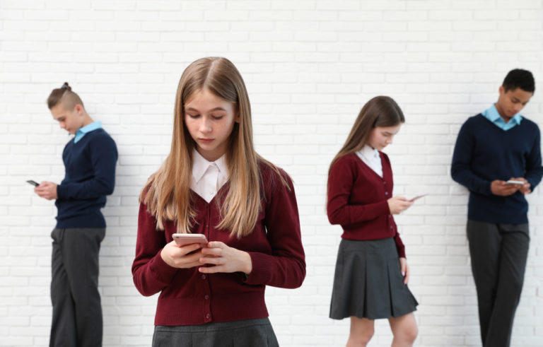 Teenagers,using,mobile,phones,at,school.,concept,of,internet,addiction