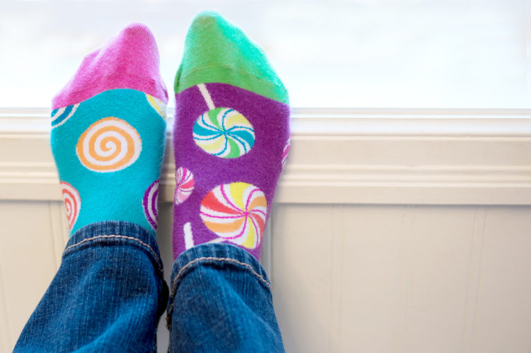A,pair,of,feet,wearing,brightly,colored,odd,socks