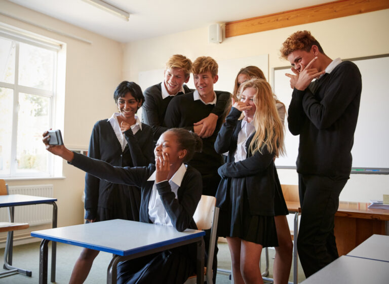 Group,of,teenage,students,posing,for,selfie,in,classroom